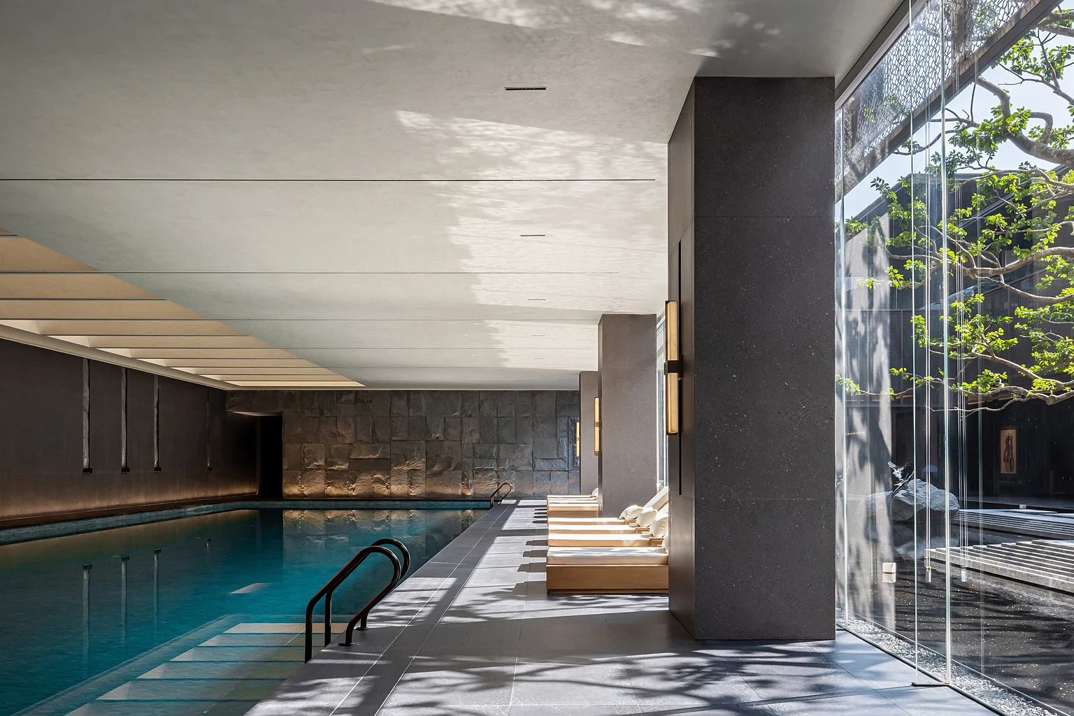 Dubai indoor pool with floor-to-ceiling glazing greenery and stone finishes