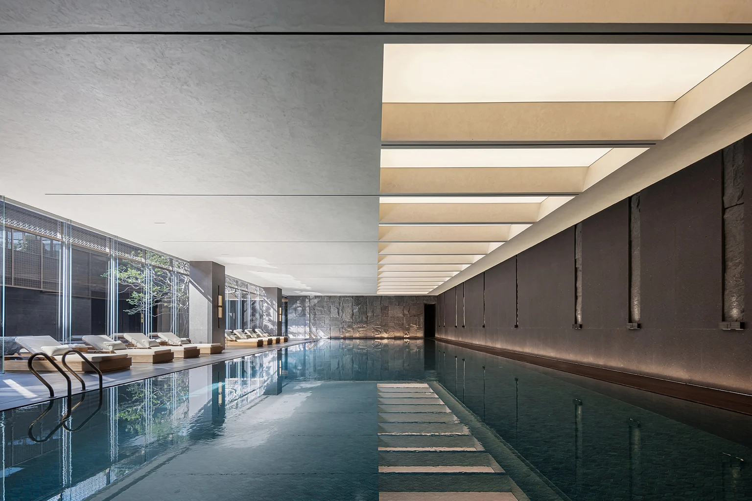Completed Dubai indoor pool with luminous coffered ceiling and dark stone water surface