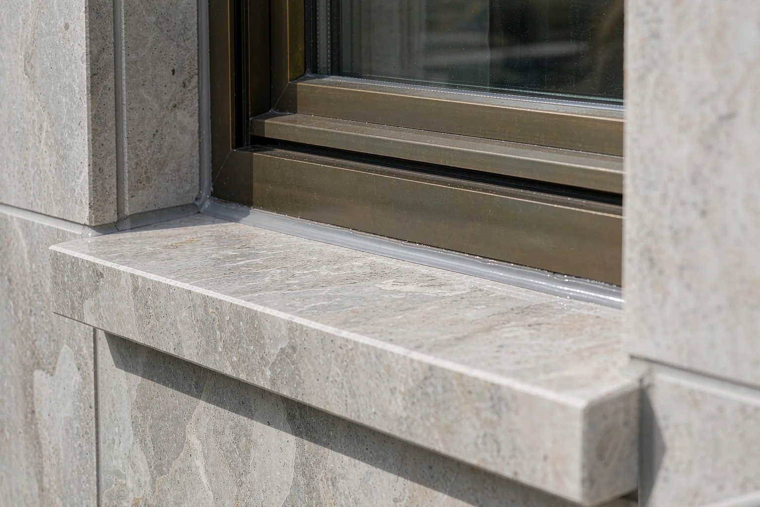 Stone sill meeting an aluminum window frame with a sealed joint detail