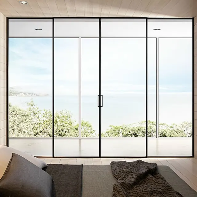 Slim dark aluminum sliding glass doors opening a living area to a coastal terrace
